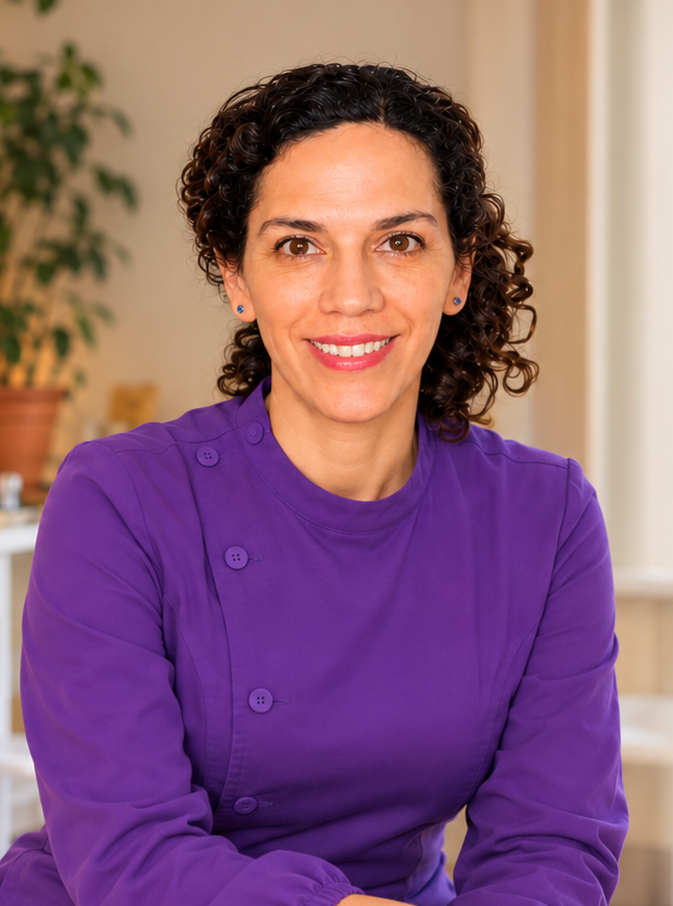 Estrella Medina, sonriente, con uniforme morado en su entorno clínico